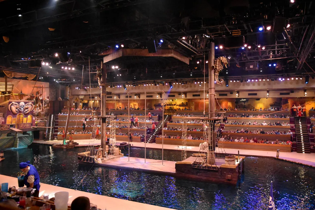 An energetic interior scene inside a theater, featuring a stage, water area, and audience seating. The image captures the thrill of live performances and immersive shows, highlighting the kind of entertainment guests can easily access during their stay.