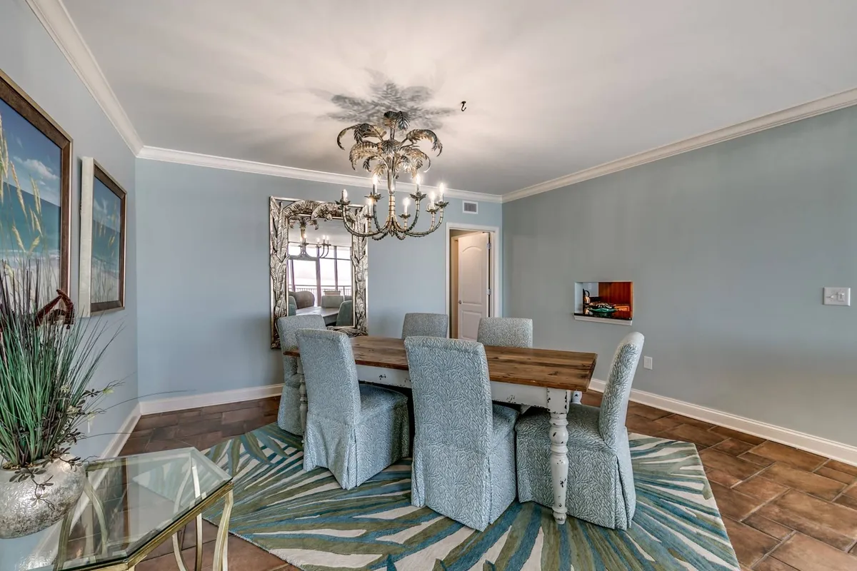 An elegant dining area with a spacious table set beneath a stylish chandelier, complemented by an area rug and tasteful wall art. The mood is relaxed yet refined, providing the ideal setting for family meals, celebrations, or lively board games. The surrounding decor enhances the inviting ambiance.